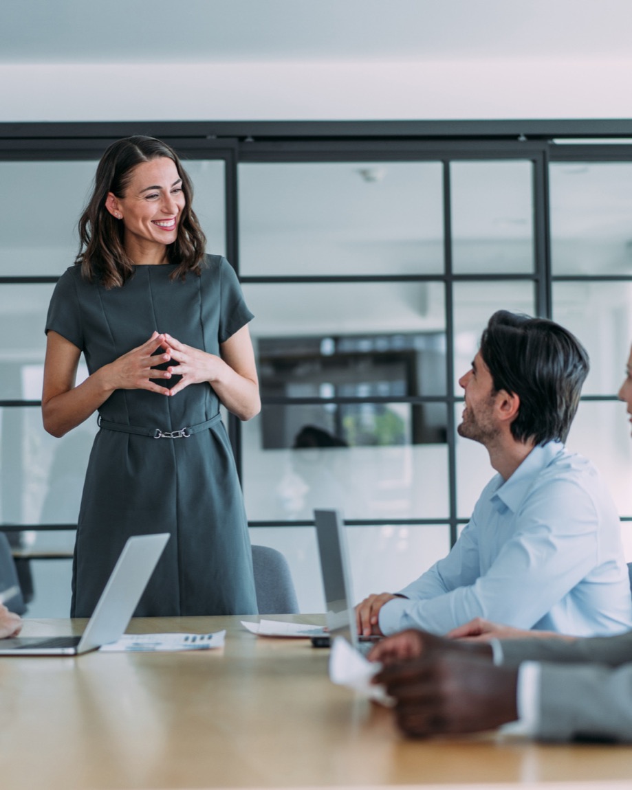 A manager leading a working session with her team around a conference table.